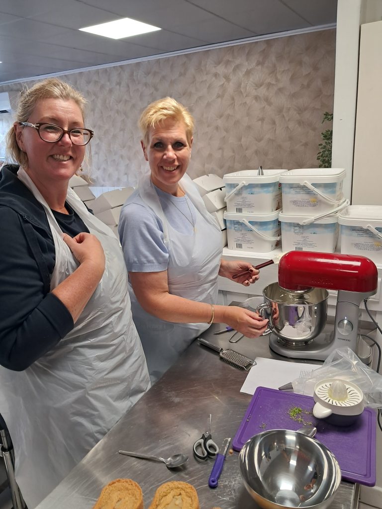 Twee deelnemers aan het werk met de mixer in de bakstudio